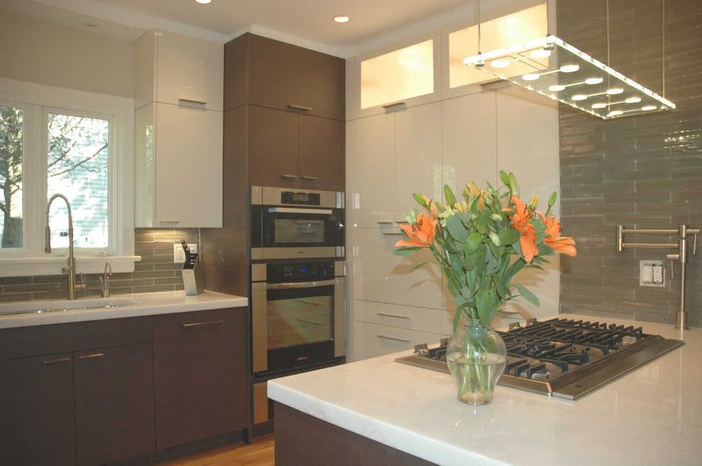 Example of a small trendy u-shaped medium tone wood floor eat-in kitchen design in New York with a double-bowl sink, flat-panel cabinets, dark wood cabinets, marble countertops, beige backsplash, glass tile backsplash, stainless steel appliances and a peninsula