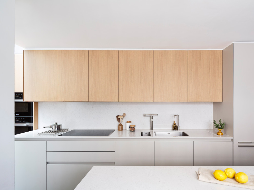 Inspiration for a medium sized contemporary l-shaped kitchen in London with flat-panel cabinets, light wood cabinets, composite countertops, beige splashback, engineered quartz splashback, an island, beige worktops, a submerged sink and integrated appliances.