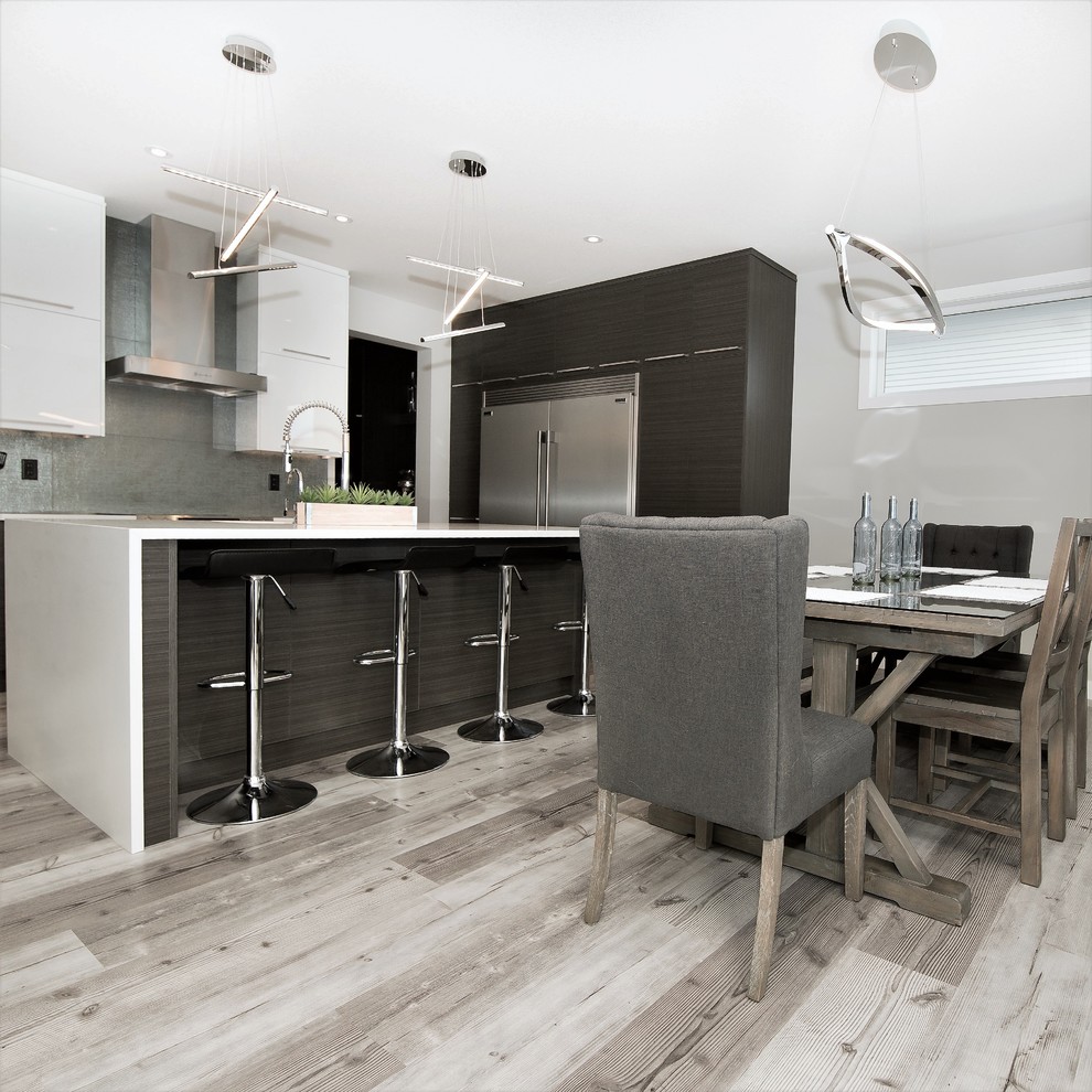 Example of a mid-sized trendy galley vinyl floor and gray floor eat-in kitchen design in Calgary with a single-bowl sink, flat-panel cabinets, white cabinets, quartzite countertops, metallic backsplash, ceramic backsplash, stainless steel appliances and an island