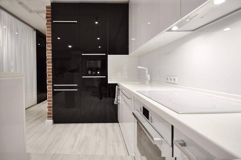 На фото: угловая кухня-гостиная в современном стиле с плоскими фасадами, белыми фасадами, белым фартуком, одинарной мойкой, светлым паркетным полом и белым полом с