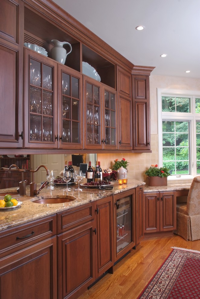 Exempel på ett mellanstort klassiskt kök, med en undermonterad diskho, luckor med upphöjd panel, skåp i mörkt trä, granitbänkskiva, beige stänkskydd, stänkskydd i keramik, rostfria vitvaror, mellanmörkt trägolv och en köksö