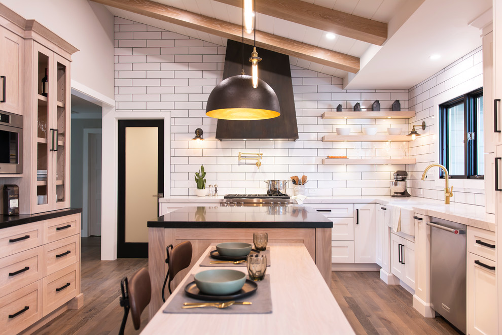 Bild på ett stort lantligt kök, med en rustik diskho, skåp i shakerstil, vita skåp, bänkskiva i kvarts, vitt stänkskydd, stänkskydd i tunnelbanekakel, rostfria vitvaror, mellanmörkt trägolv, en köksö och brunt golv