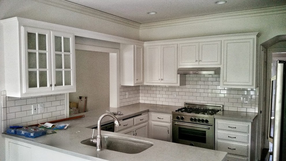 Small arts and crafts u-shaped eat-in kitchen photo in San Francisco with stainless steel countertops, stainless steel appliances, an undermount sink, recessed-panel cabinets, white cabinets, white backsplash, subway tile backsplash and a peninsula