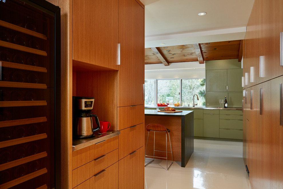 Exempel på ett modernt kök, med en integrerad diskho, släta luckor, gröna skåp, bänkskiva i rostfritt stål, integrerade vitvaror och en köksö