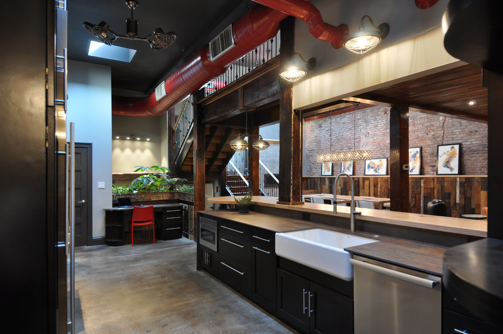 Eat-in kitchen - large industrial u-shaped concrete floor and gray floor eat-in kitchen idea in St Louis with a farmhouse sink, shaker cabinets, dark wood cabinets, wood countertops, white backsplash, subway tile backsplash, stainless steel appliances and a peninsula
