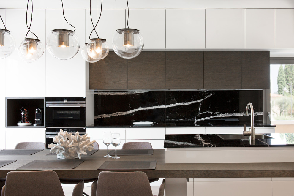 Exempel på ett modernt kök, med släta luckor, vita skåp, svart stänkskydd, stänkskydd i marmor, svarta vitvaror och en köksö