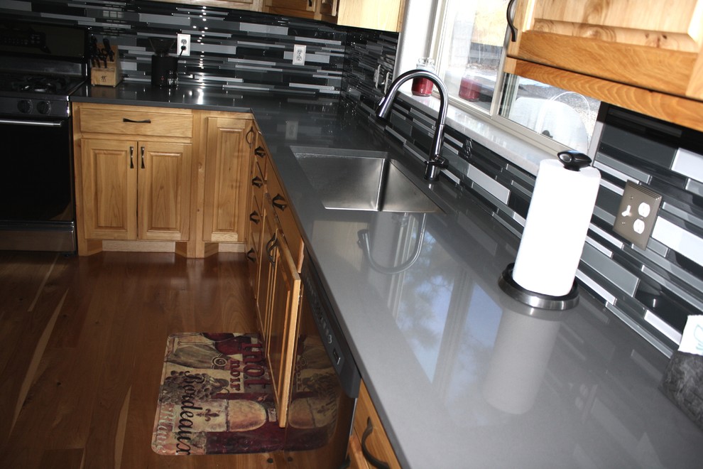 Immagine di un cucina con isola centrale design con lavello sottopiano, top in quarzo composito, paraspruzzi nero e paraspruzzi con piastrelle di vetro