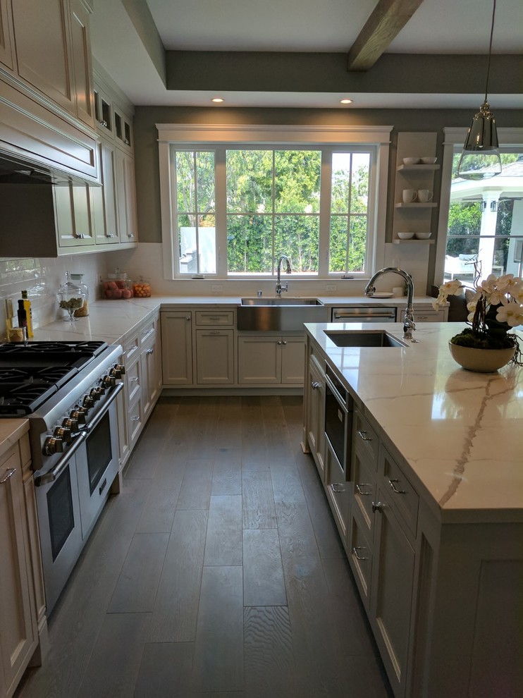 Inspiration for a large modern u-shaped porcelain tile, gray floor and exposed beam eat-in kitchen remodel in Orange County with an undermount sink, recessed-panel cabinets, white cabinets, quartz countertops, white backsplash, stone slab backsplash, stainless steel appliances, an island and white countertops