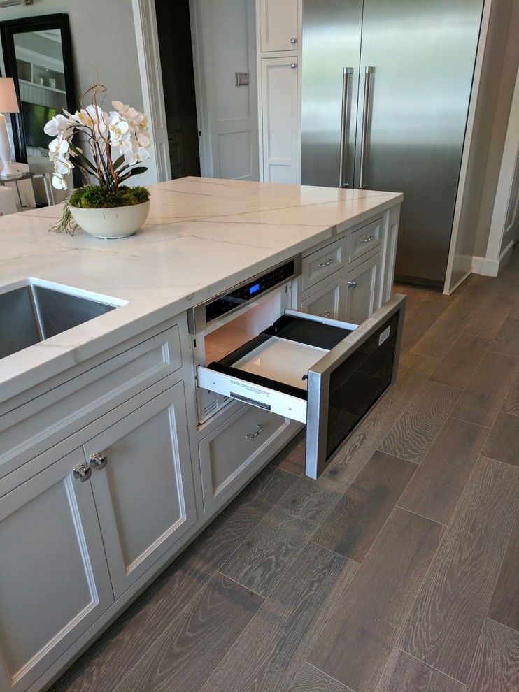 Example of a large minimalist u-shaped porcelain tile, gray floor and exposed beam eat-in kitchen design in Orange County with an undermount sink, recessed-panel cabinets, white cabinets, quartz countertops, white backsplash, stone slab backsplash, stainless steel appliances, an island and white countertops