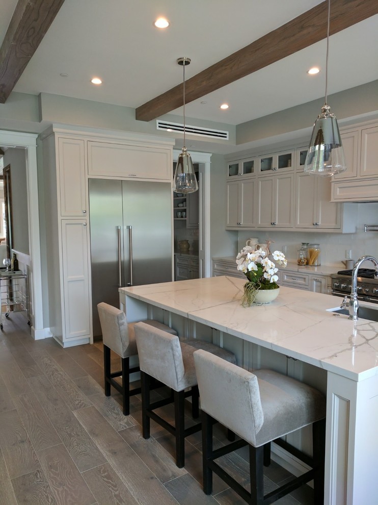 Example of a large minimalist u-shaped porcelain tile, gray floor and exposed beam eat-in kitchen design in Orange County with an undermount sink, recessed-panel cabinets, white cabinets, quartz countertops, white backsplash, stone slab backsplash, stainless steel appliances, an island and white countertops