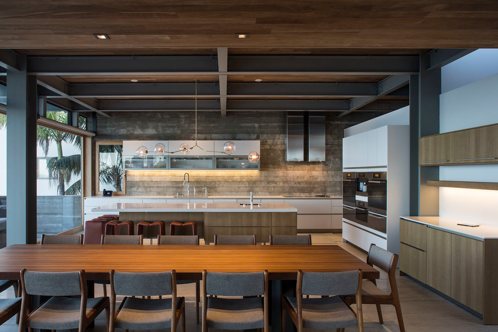 This is an example of a contemporary kitchen/diner in Orange County with a submerged sink, flat-panel cabinets, white cabinets, stainless steel appliances, an island and grey splashback.