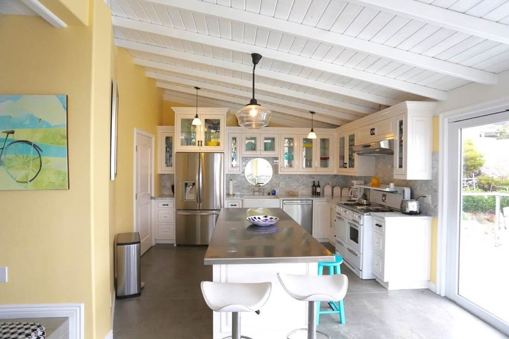 Example of a mid-sized beach style l-shaped concrete floor and brown floor eat-in kitchen design in Orange County with beaded inset cabinets, white cabinets, quartzite countertops, white backsplash, stone tile backsplash, white appliances and an island