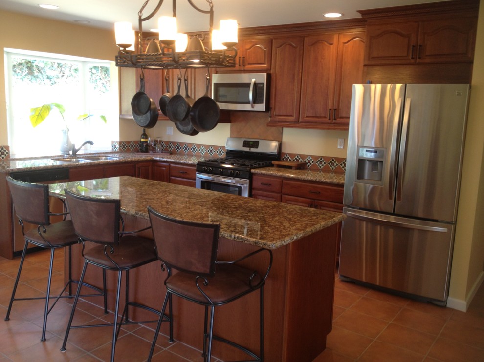 Example of a mid-sized tuscan l-shaped terra-cotta tile and brown floor eat-in kitchen design in Orange County with a double-bowl sink, raised-panel cabinets, dark wood cabinets, granite countertops, stainless steel appliances, an island and brown countertops