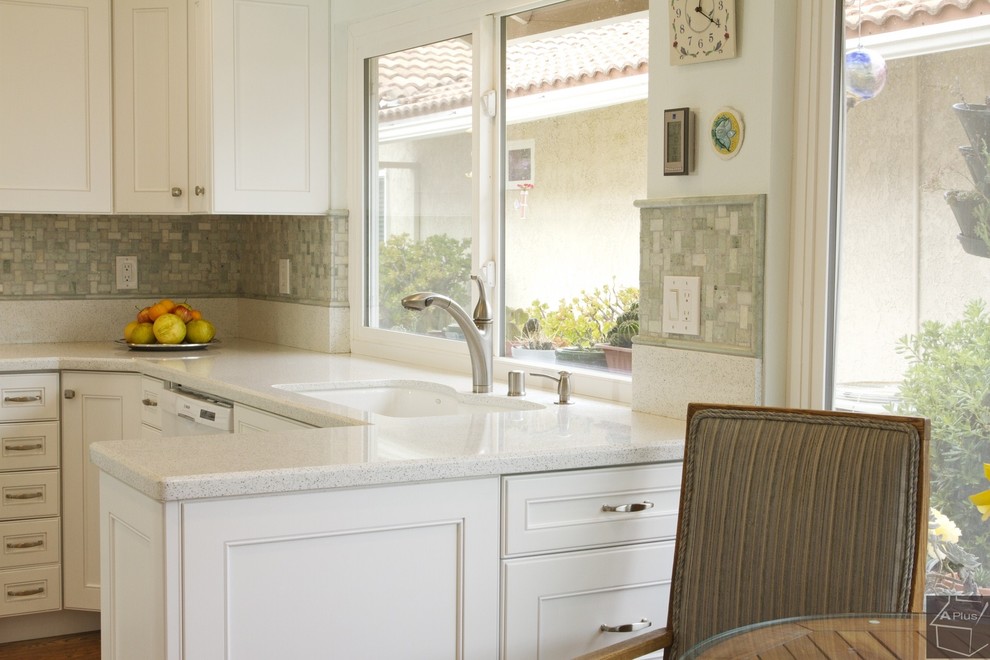 Exempel på ett mellanstort klassiskt kök, med en nedsänkt diskho, luckor med infälld panel, vita skåp, bänkskiva i kvarts, grönt stänkskydd, stänkskydd i mosaik, vita vitvaror, ljust trägolv och en halv köksö