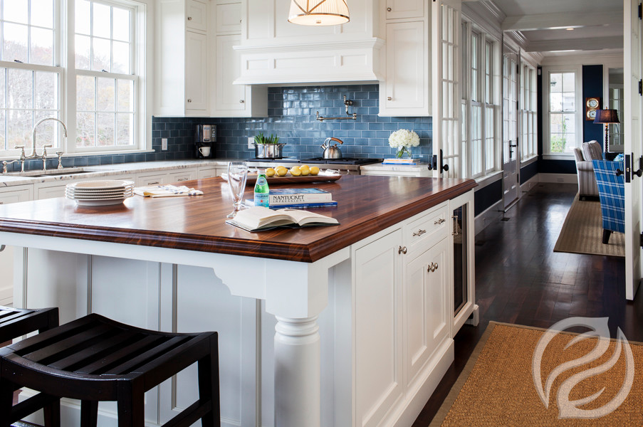 Klassische Küche mit Kassettenfronten, weißen Schränken, Arbeitsplatte aus Holz, Küchenrückwand in Blau, Rückwand aus Keramikfliesen, braunem Holzboden, brauner Arbeitsplatte, Küchengeräten aus Edelstahl und Kücheninsel in Boston