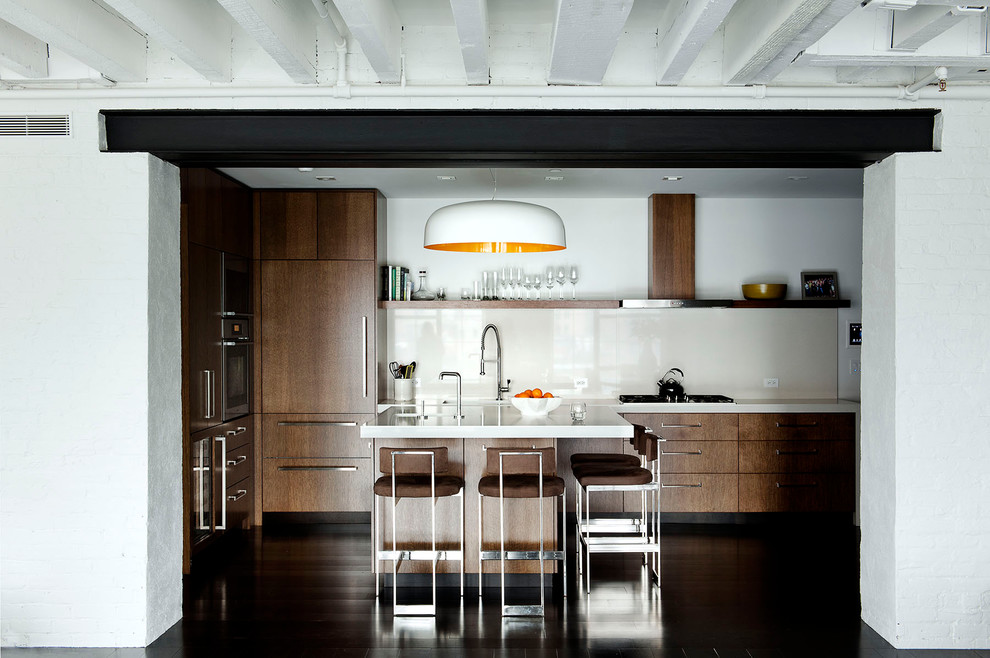 Immagine di una cucina industriale con ante lisce, ante in legno bruno, paraspruzzi bianco, elettrodomestici da incasso e top in quarzo composito