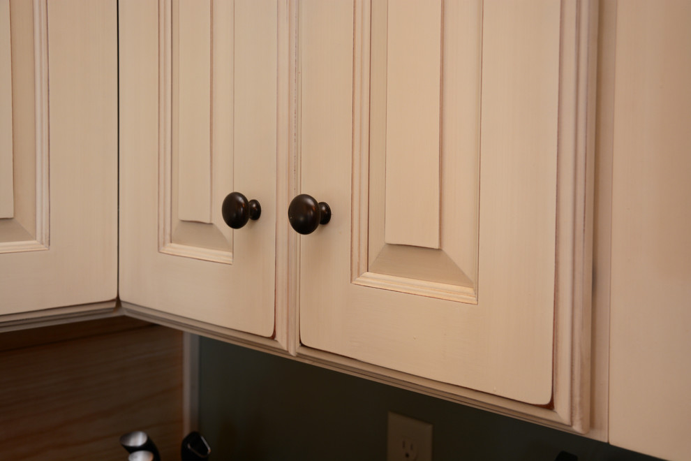 Rustik inredning av ett mellanstort kök, med en rustik diskho, luckor med upphöjd panel, gula skåp, granitbänkskiva, rostfria vitvaror, mörkt trägolv och en köksö