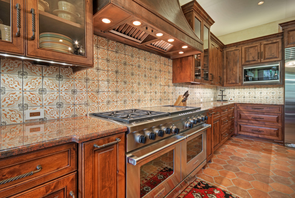 オースティンにある地中海スタイルのおしゃれなキッチン (ガラス扉のキャビネット、シルバーの調理設備、御影石カウンター) の写真