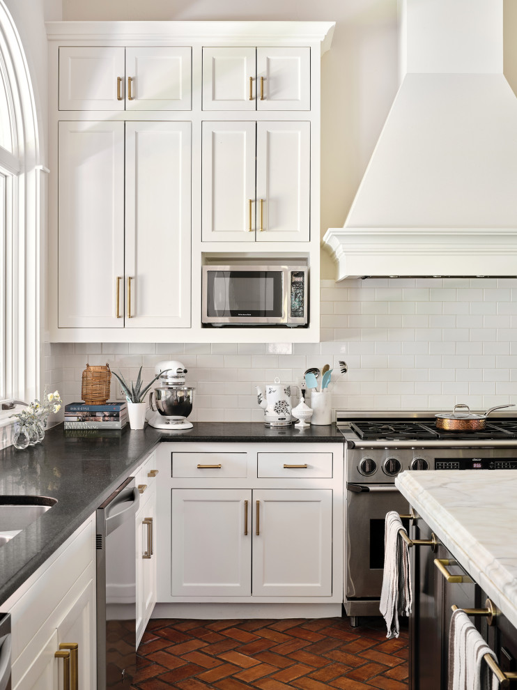 Klassisk inredning av ett mycket stort u-kök, med en undermonterad diskho, skåp i shakerstil, vita skåp, marmorbänkskiva, vitt stänkskydd, stänkskydd i tunnelbanekakel, rostfria vitvaror, tegelgolv och en köksö