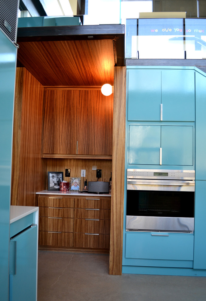 На фото: кухня в стиле модернизм с плоскими фасадами, бирюзовыми фасадами, столешницей из кварцевого агломерата и техникой под мебельный фасад с