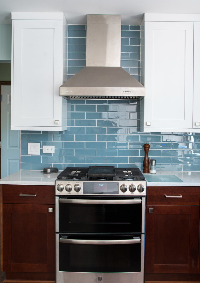 シカゴにある高級な中くらいなミッドセンチュリースタイルのおしゃれなキッチン (シングルシンク、シェーカースタイル扉のキャビネット、クオーツストーンカウンター、青いキッチンパネル、ガラスタイルのキッチンパネル、シルバーの調理設備、無垢フローリング、赤い床、白いキッチンカウンター) の写真