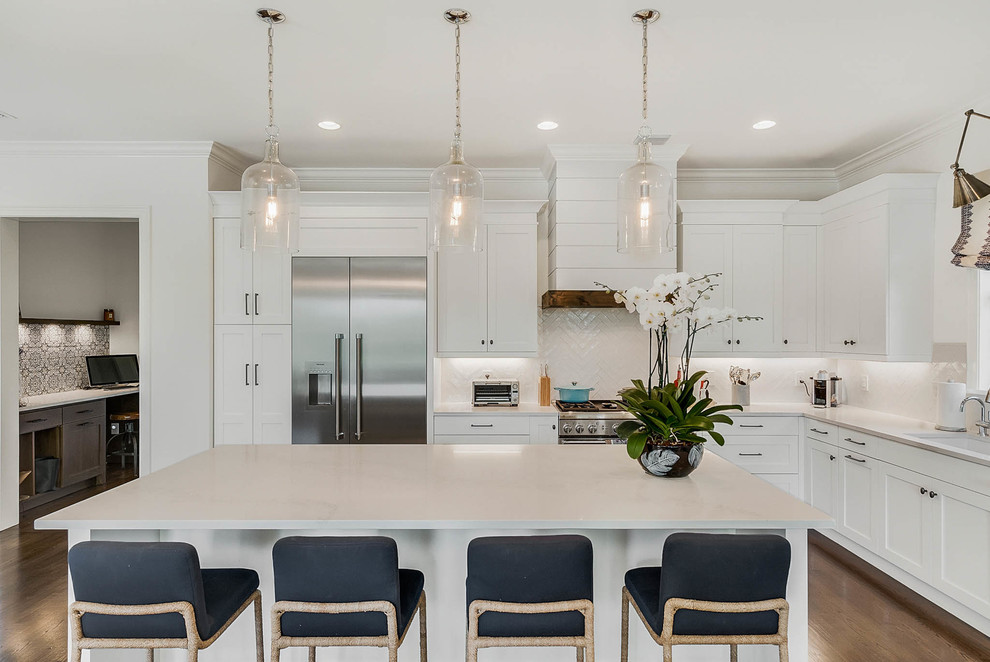 Large transitional l-shaped medium tone wood floor and brown floor open concept kitchen photo in Orlando with an undermount sink, shaker cabinets, white cabinets, marble countertops, white backsplash, ceramic backsplash, stainless steel appliances and an island