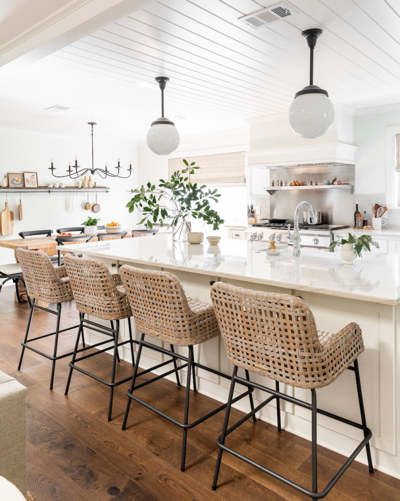 Open concept kitchen - mid-sized transitional medium tone wood floor and brown floor open concept kitchen idea in Dallas with white cabinets, quartzite countertops, white backsplash, terra-cotta backsplash, stainless steel appliances, an island and white countertops