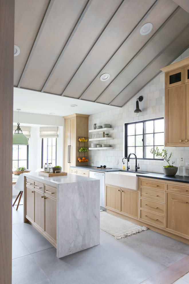 Maritim inredning av ett kök och matrum, med skåp i ljust trä, marmorbänkskiva, en rustik diskho, stänkskydd i marmor, rostfria vitvaror, klinkergolv i keramik, en köksö och grått golv