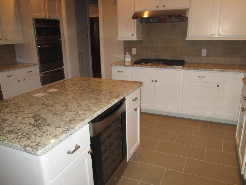 Exempel på ett amerikanskt kök, med en nedsänkt diskho, vita skåp, granitbänkskiva, brunt stänkskydd, klinkergolv i keramik och en köksö