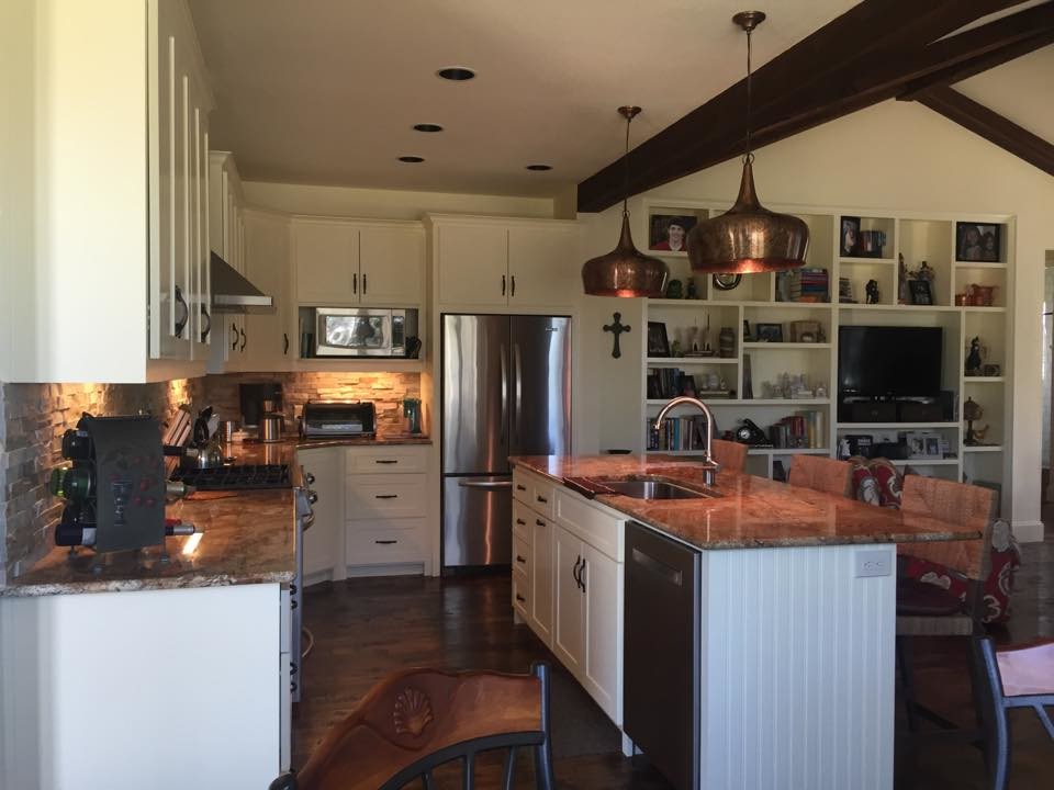 Inspiration for a mid-sized southwestern l-shaped dark wood floor and brown floor open concept kitchen remodel in Dallas with an undermount sink, shaker cabinets, white cabinets, granite countertops, gray backsplash, stone tile backsplash, stainless steel appliances and an island