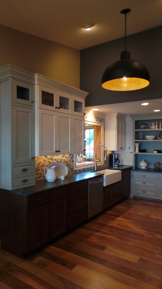Klassisk inredning av ett kök, med en rustik diskho, luckor med infälld panel, vita skåp, bänkskiva i täljsten, flerfärgad stänkskydd, stänkskydd i glaskakel och rostfria vitvaror