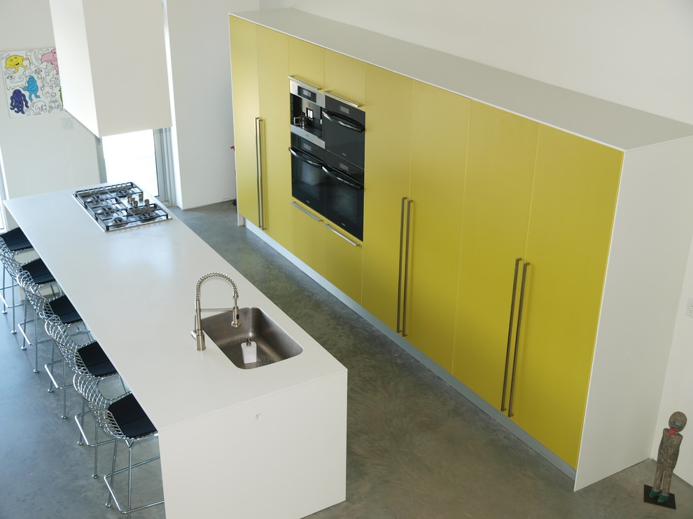 バンクーバーにあるラグジュアリーな広いモダンスタイルのおしゃれなキッチン (アンダーカウンターシンク、フラットパネル扉のキャビネット、黄色いキャビネット、シルバーの調理設備、コンクリートの床) の写真