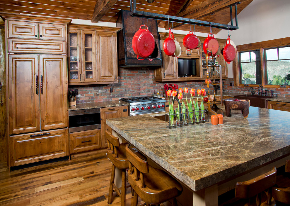 Große Klassische Wohnküche in U-Form mit Unterbauwaschbecken, profilierten Schrankfronten, hellbraunen Holzschränken, Küchenrückwand in Rot, Küchengeräten aus Edelstahl, braunem Holzboden, zwei Kücheninseln, Rückwand aus Backstein und beigem Boden in Denver
