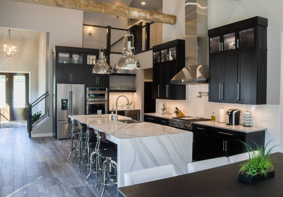 Large urban l-shaped light wood floor and gray floor open concept kitchen photo in Other with a farmhouse sink, shaker cabinets, black cabinets, quartz countertops, white backsplash, subway tile backsplash, colored appliances, an island and white countertops