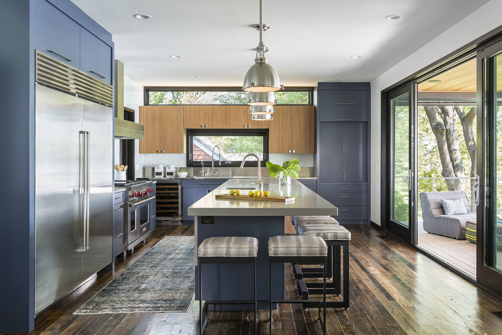 Foto på ett stort funkis kök, med en integrerad diskho, släta luckor, blå skåp, bänkskiva i kvarts, grått stänkskydd, rostfria vitvaror, mellanmörkt trägolv och en köksö
