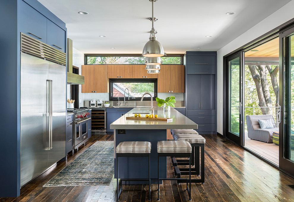 Moderne Küche in L-Form mit integriertem Waschbecken, flächenbündigen Schrankfronten, blauen Schränken, Edelstahl-Arbeitsplatte, Küchengeräten aus Edelstahl, dunklem Holzboden und Kücheninsel in Minneapolis
