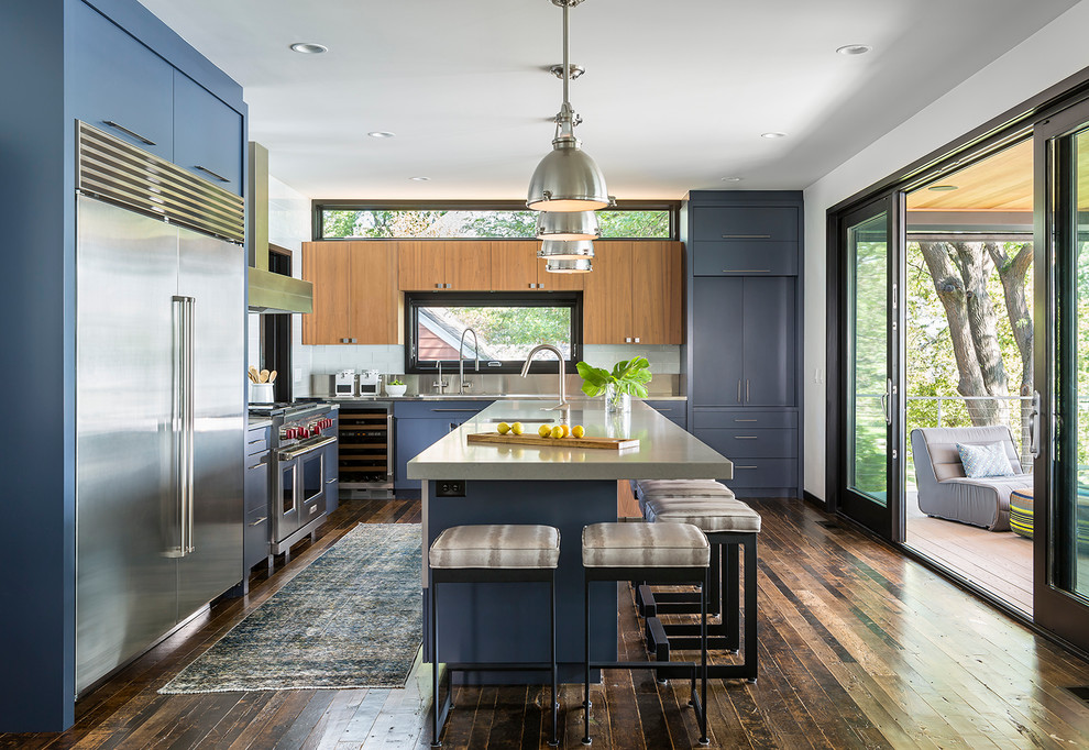 Foto di una cucina minimal con lavello integrato, ante lisce, ante blu, top in acciaio inossidabile, elettrodomestici in acciaio inossidabile e parquet scuro