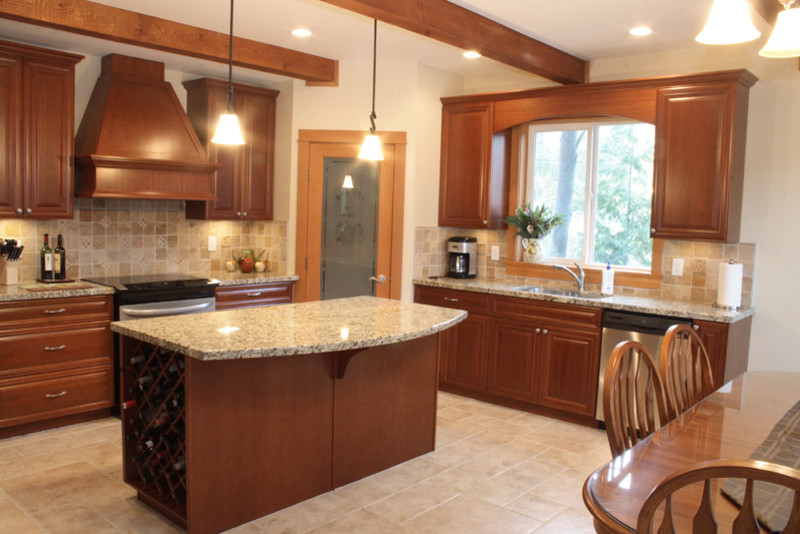 Photo of a traditional l-shaped kitchen/diner in Vancouver with a submerged sink, raised-panel cabinets, medium wood cabinets, beige splashback, stainless steel appliances and an island.