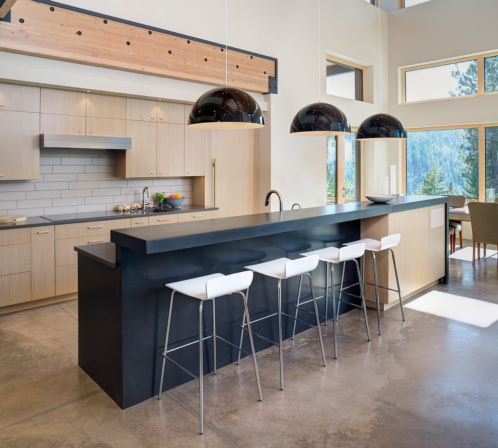 Inspiration for a mid-sized modern galley cement tile floor open concept kitchen remodel in Seattle with an undermount sink, flat-panel cabinets, light wood cabinets, concrete countertops, gray backsplash, subway tile backsplash, stainless steel appliances and an island