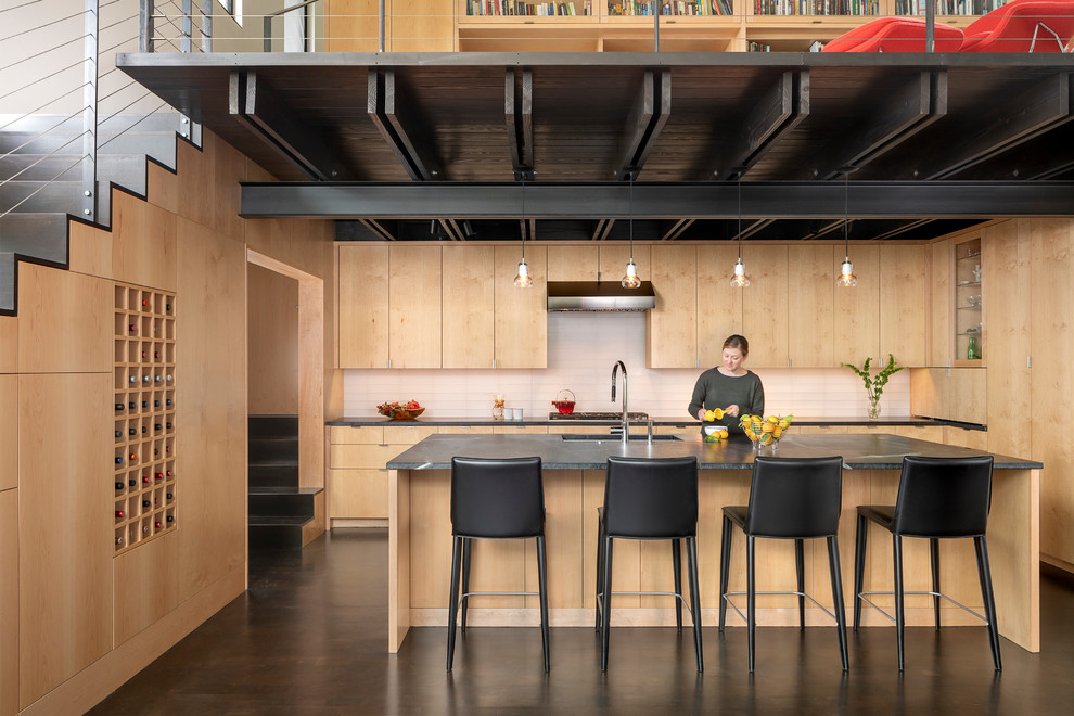 Große Rustikale Küche mit flächenbündigen Schrankfronten, hellen Holzschränken, Küchenrückwand in Weiß, Kücheninsel, braunem Boden und schwarzer Arbeitsplatte in Austin