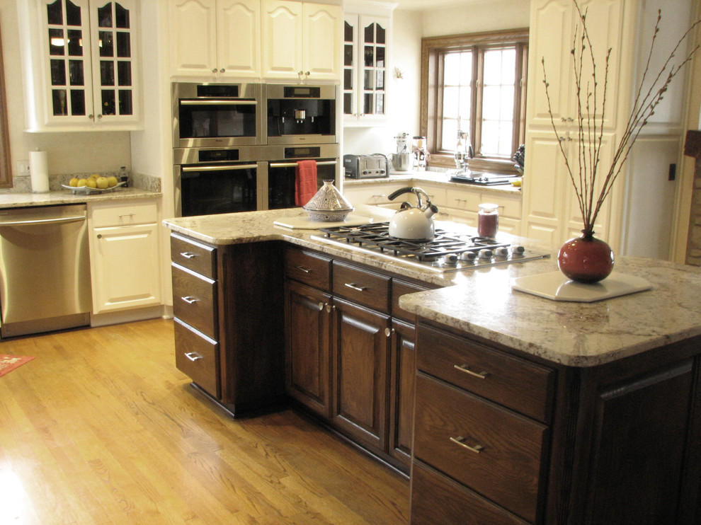 Aménagement d'une grande cuisine américaine classique en L et bois brun avec un placard avec porte à panneau surélevé, plan de travail en marbre et îlot.