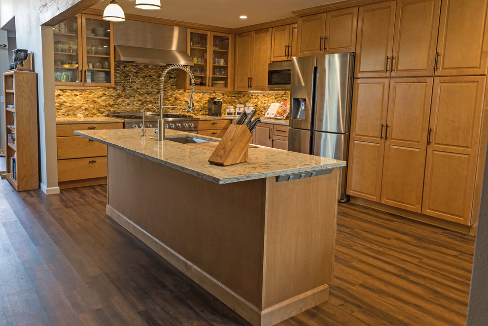 Inspiration for a mid-sized transitional l-shaped vinyl floor and brown floor eat-in kitchen remodel in Orange County with an undermount sink, raised-panel cabinets, medium tone wood cabinets, quartz countertops, brown backsplash, glass tile backsplash, stainless steel appliances, an island and multicolored countertops