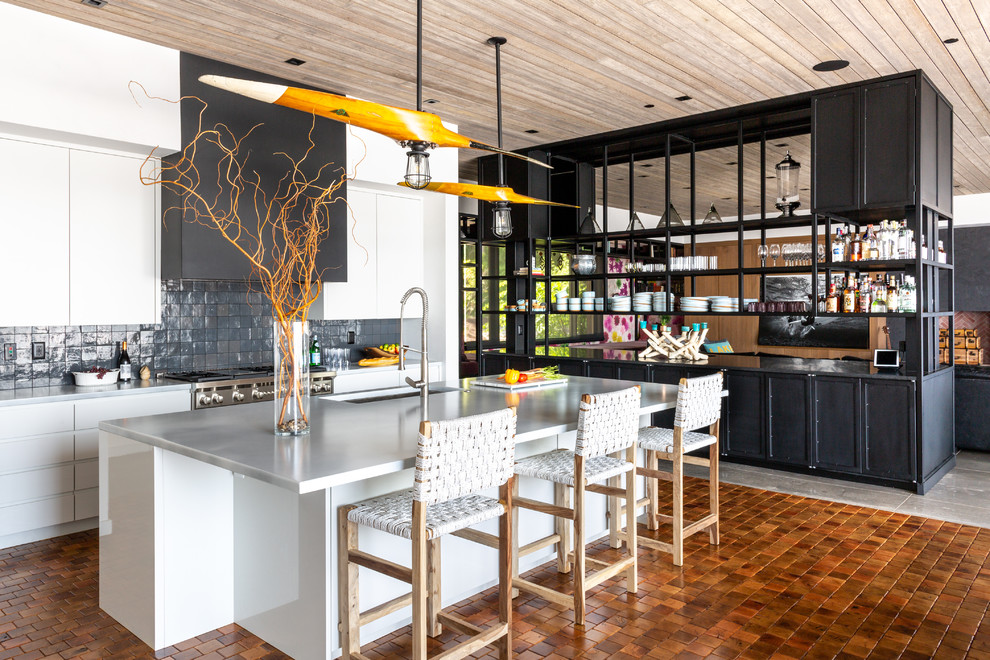 Esempio di una cucina costiera con ante lisce, lavello sottopiano, paraspruzzi nero, elettrodomestici in acciaio inossidabile, pavimento arancione e top grigio