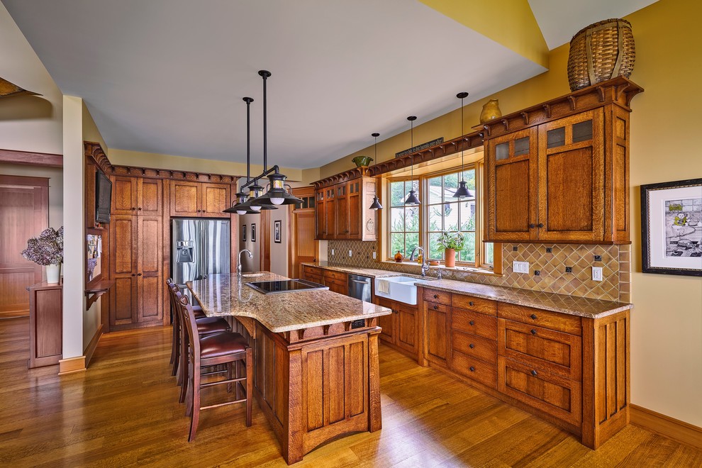Idéer för att renovera ett mellanstort amerikanskt kök, med en rustik diskho, luckor med infälld panel, skåp i mellenmörkt trä, granitbänkskiva, beige stänkskydd, stänkskydd i stenkakel, rostfria vitvaror, ljust trägolv och en köksö