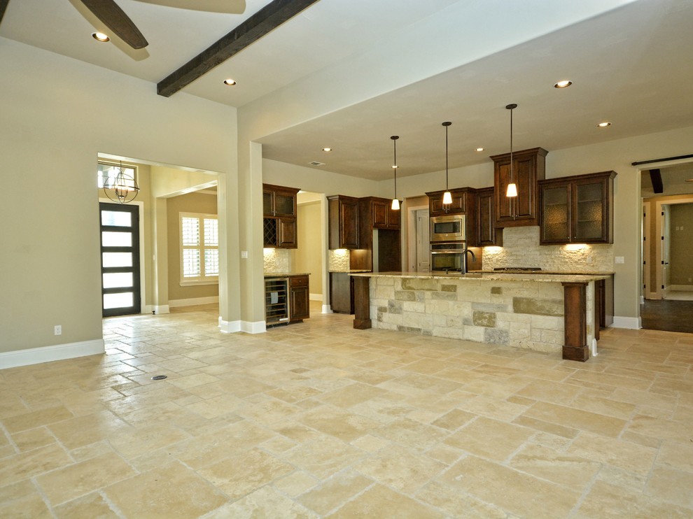 Inspiration for a mid-sized rustic l-shaped travertine floor eat-in kitchen remodel in Austin with an undermount sink, raised-panel cabinets, dark wood cabinets, granite countertops, beige backsplash, stainless steel appliances and an island