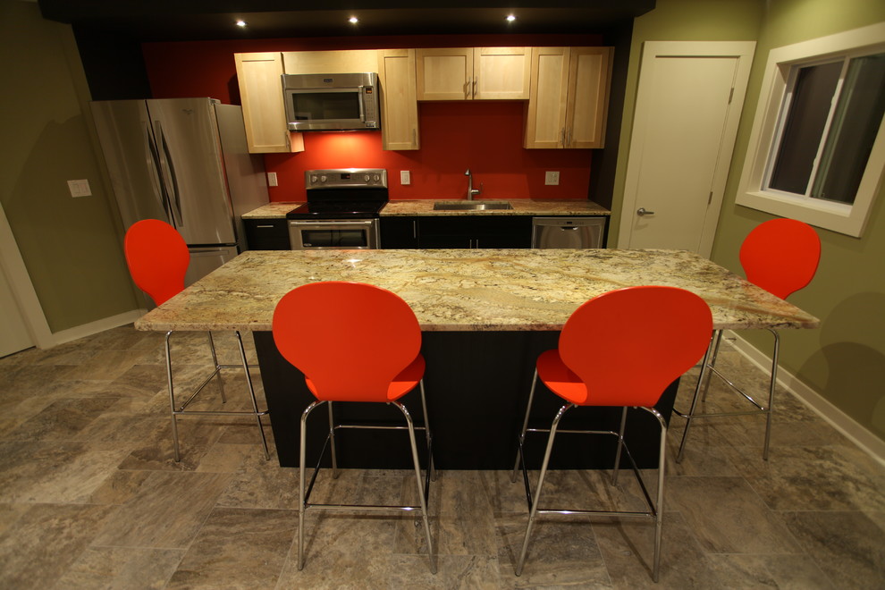 Cette photo montre une cuisine linéaire moderne en bois clair de taille moyenne avec un évier encastré, un placard à porte shaker, un plan de travail en granite, une crédence rouge, un électroménager en acier inoxydable, un sol en calcaire et îlot.