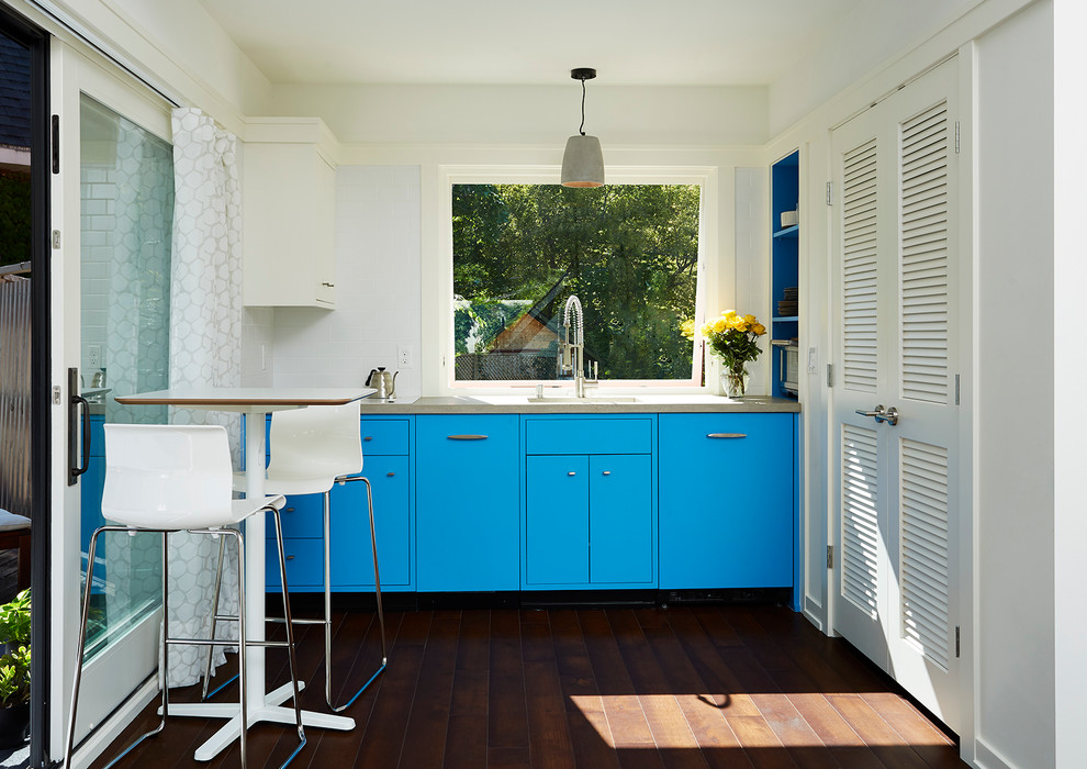 На фото: маленькая прямая кухня в современном стиле с обеденным столом, одинарной мойкой, синими фасадами, темным паркетным полом, столешницей из бетона и шторами на окнах без острова для на участке и в саду