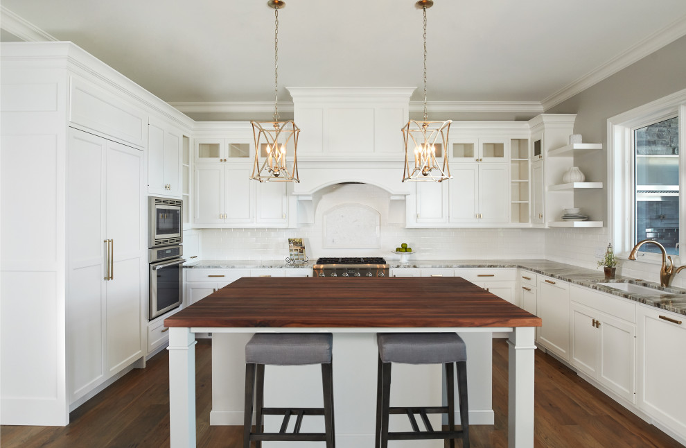 Eat-in kitchen - mid-sized coastal u-shaped medium tone wood floor and brown floor eat-in kitchen idea in Grand Rapids with an undermount sink, flat-panel cabinets, white cabinets, quartz countertops, white backsplash, ceramic backsplash, stainless steel appliances and an island