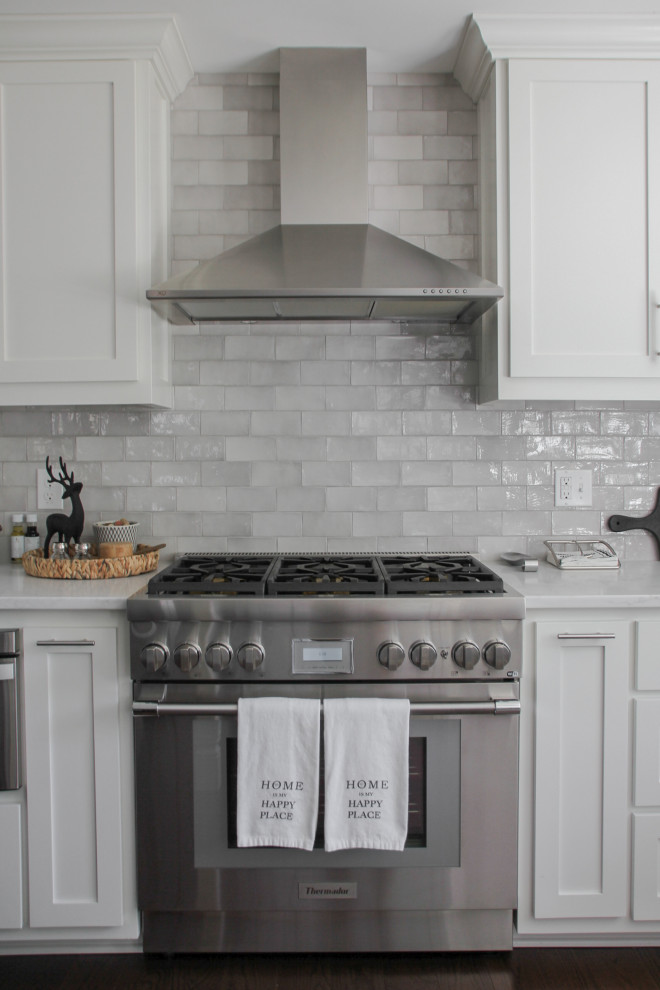 Foto på ett litet maritimt vit kök, med en rustik diskho, skåp i shakerstil, vita skåp, bänkskiva i kvarts, grått stänkskydd, stänkskydd i keramik, rostfria vitvaror, mörkt trägolv, en köksö och brunt golv