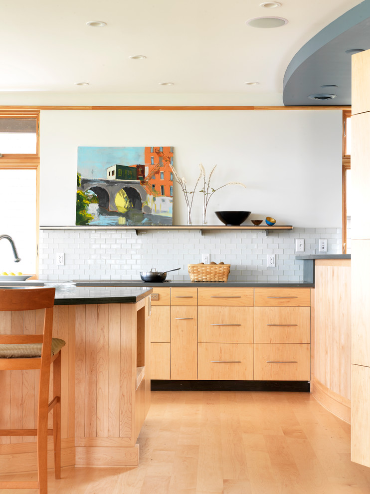 На фото: кухня в современном стиле с плоскими фасадами, светлыми деревянными фасадами, белым фартуком и фартуком из плитки кабанчик с
